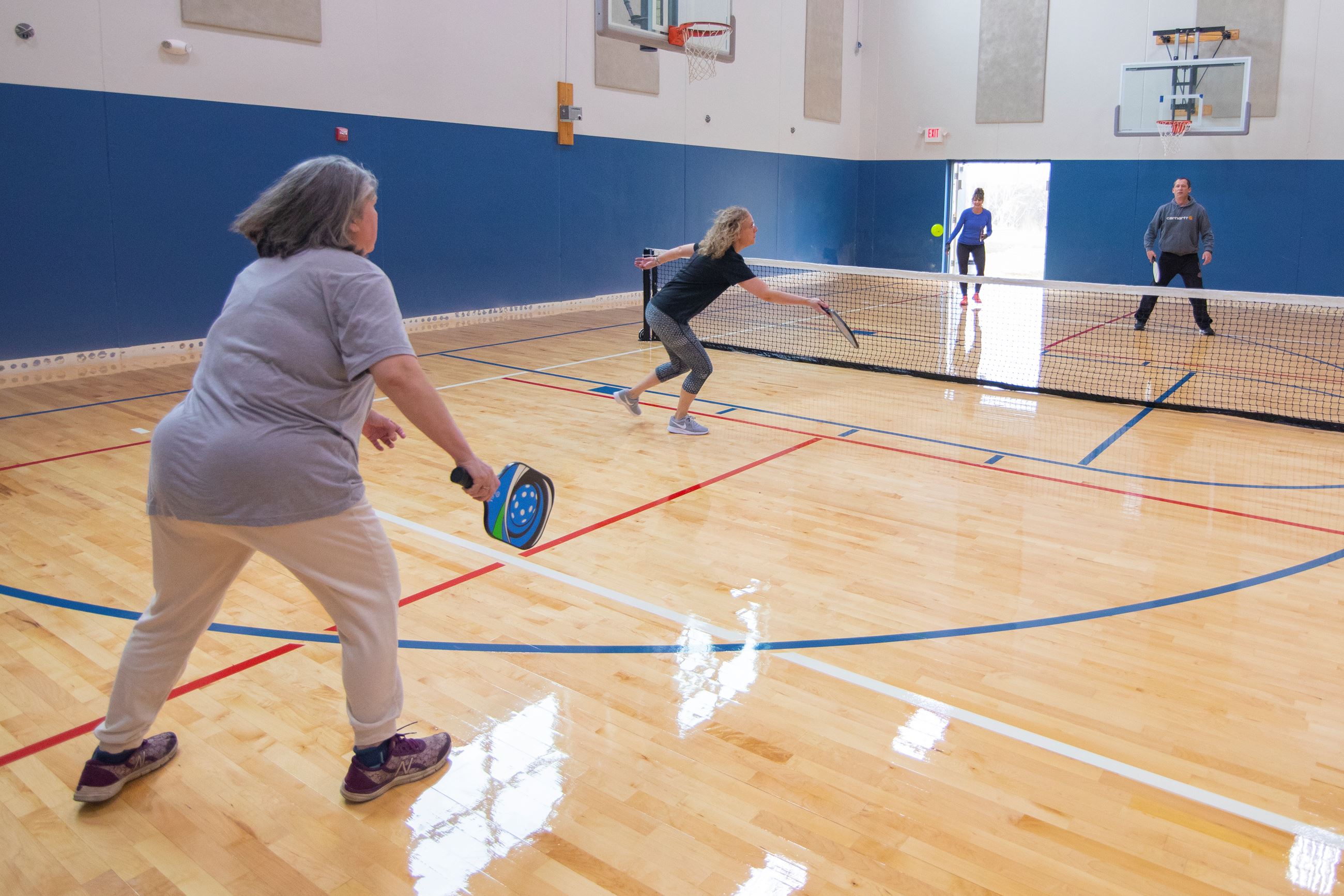 People in a gymnasium playing pickleball